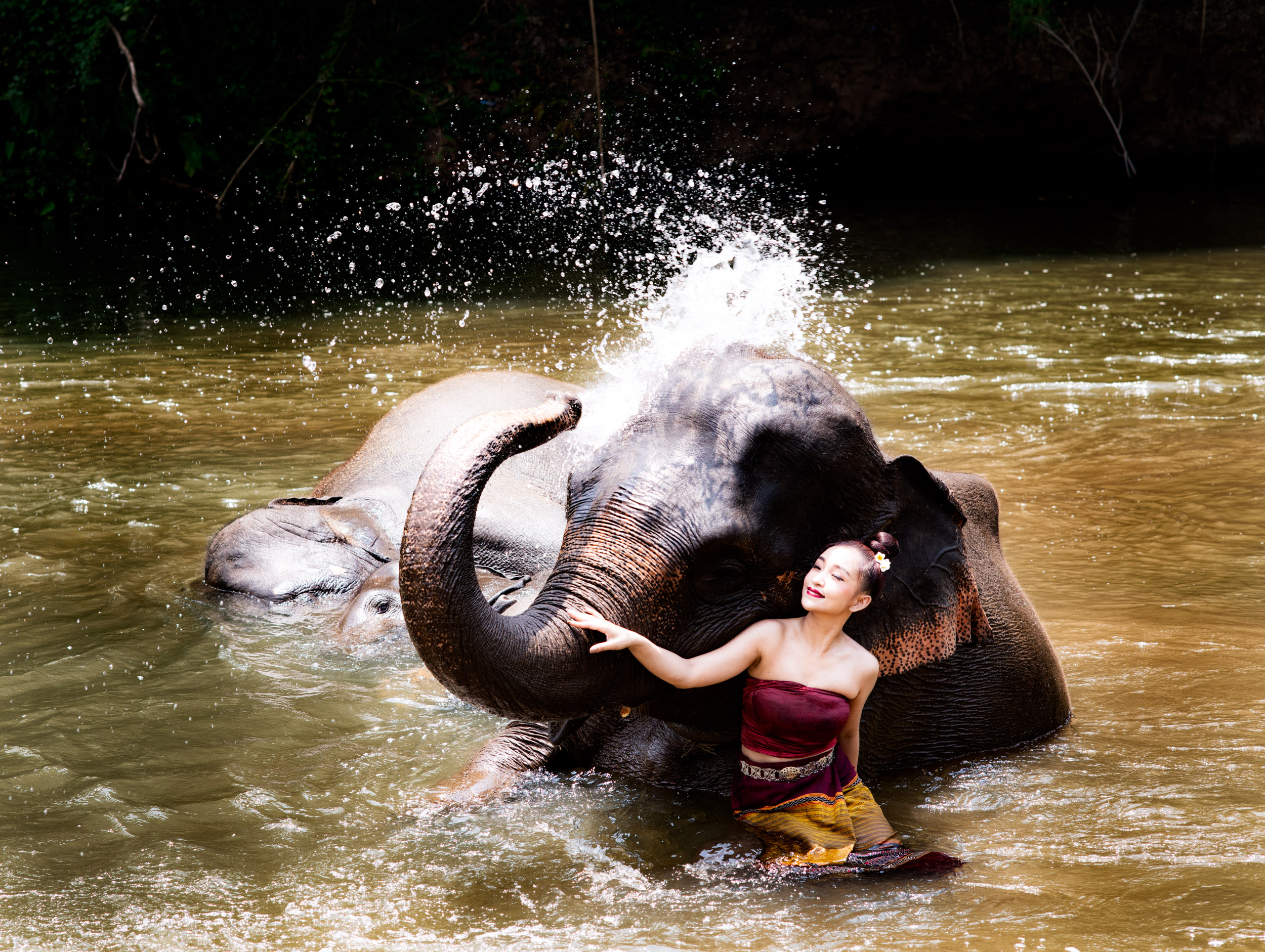 woman and elephant in a river for article on northern Thailand weather